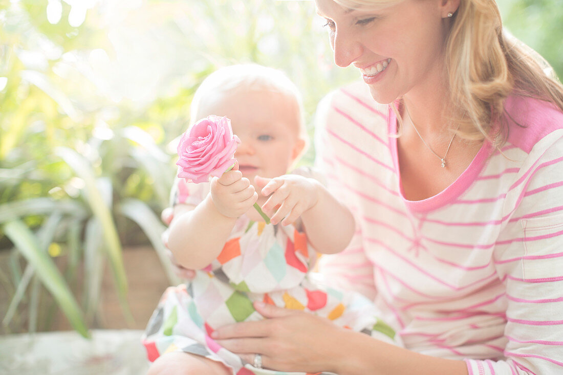 Mother and baby girl playing with flower