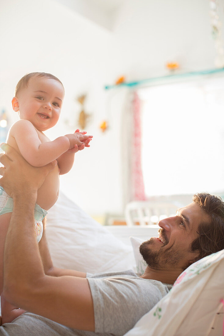 Father holding baby boy on sofa