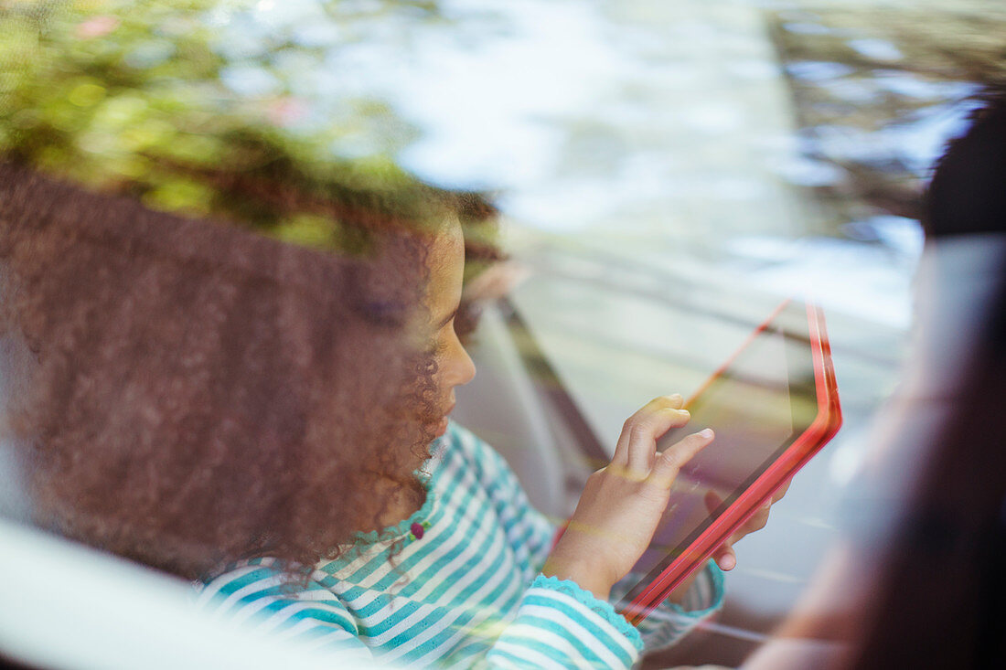 Girl using tablet in back seat of car