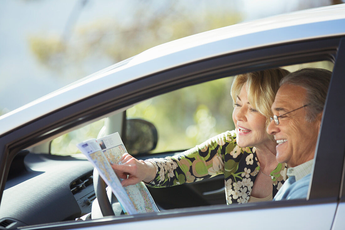 Senior couple looking at map inside car