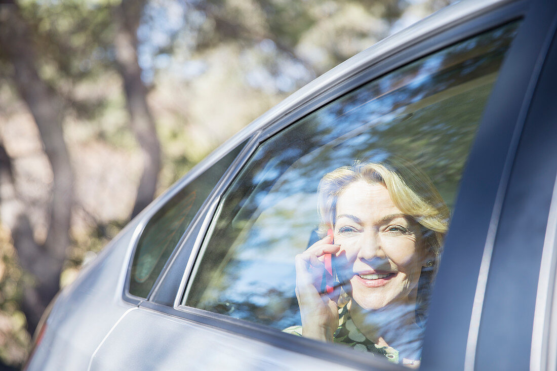 Senior woman talking on cell phone in car