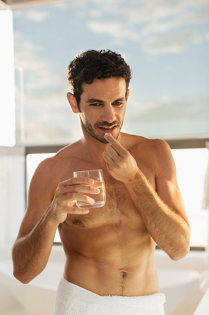 Man taking medication in bathroom