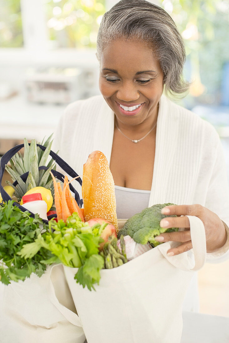 Happy senior woman unpacking groceries