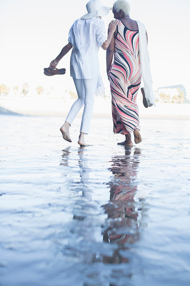 Women walking barefoot on beach