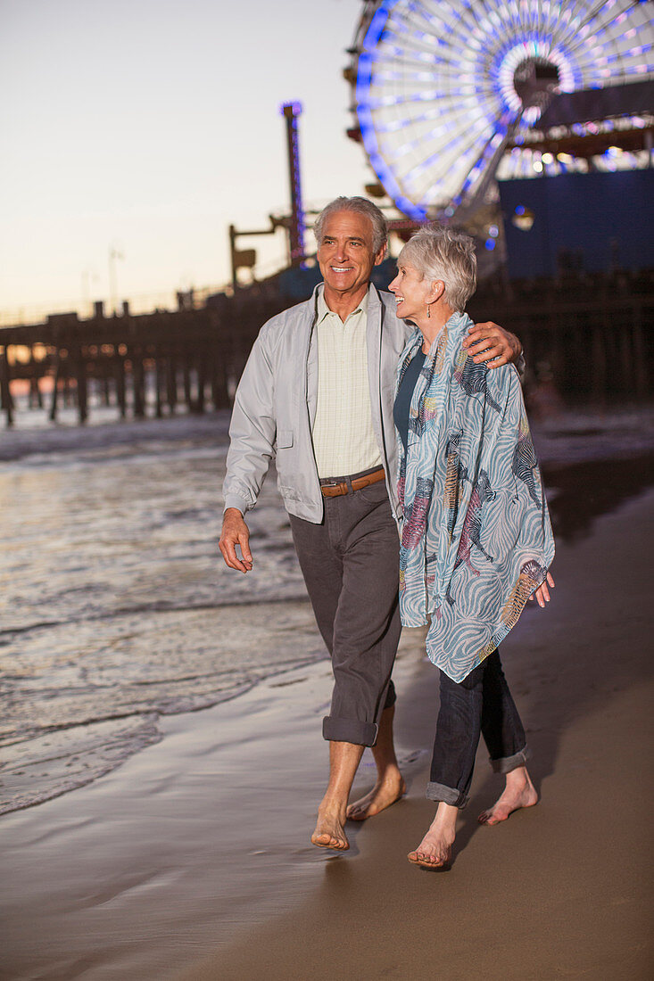 Senior couple walking on beach at sunset