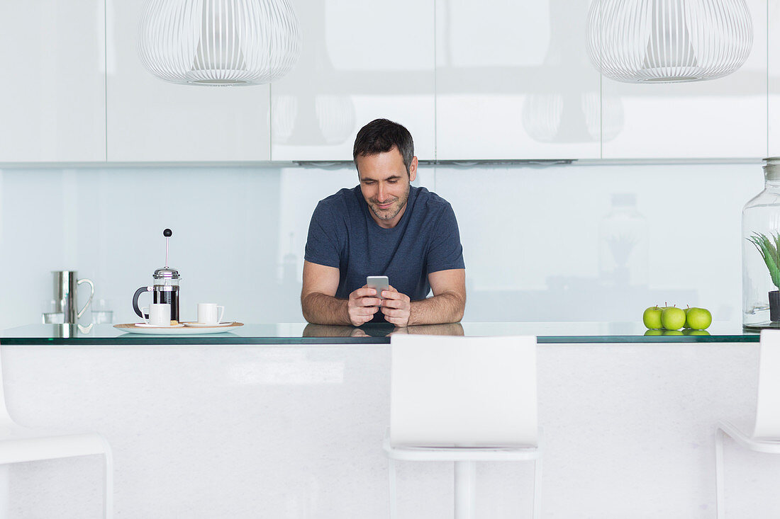 Man using cell phone in modern kitchen