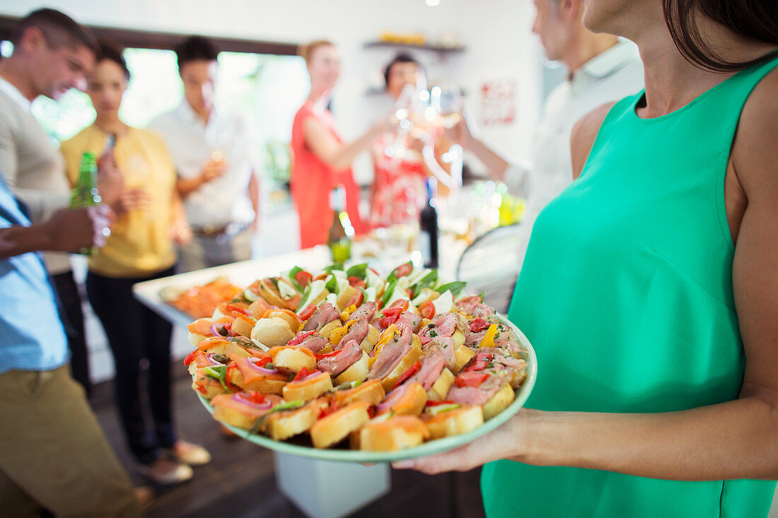 Woman serving tray of food at party