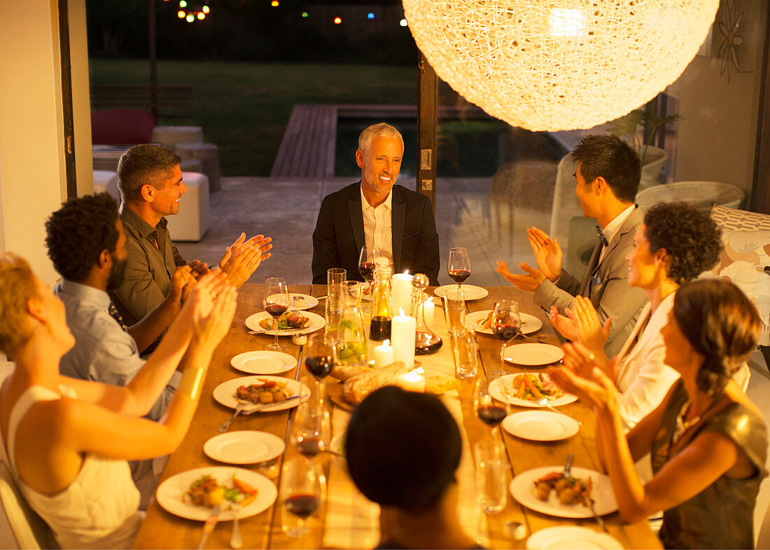 Friends applauding man at dinner party