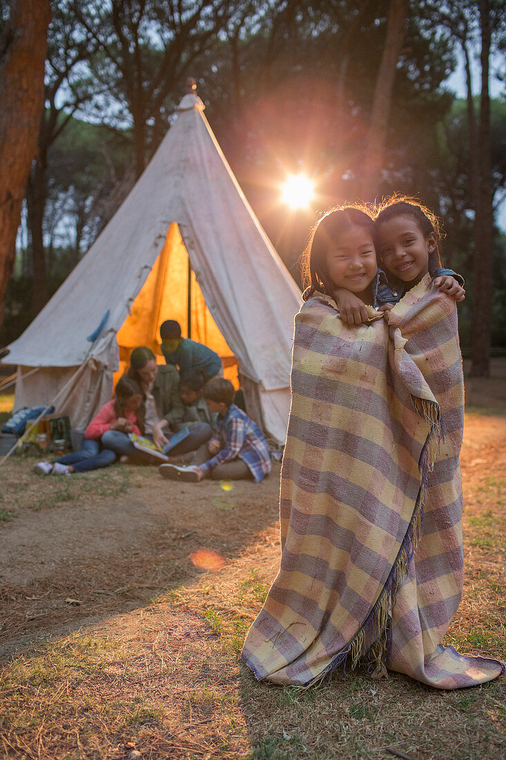 Children wrapped in blanket at campsite