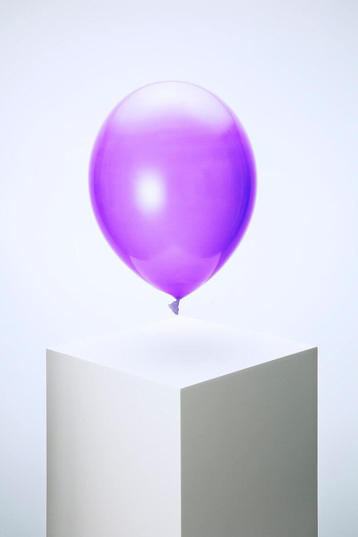 Purple balloon hovering over pedestal