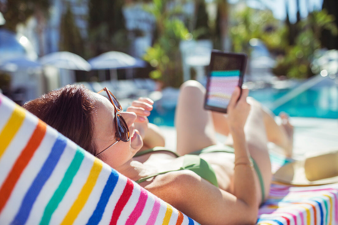 Smiling woman with tablet sunbathing