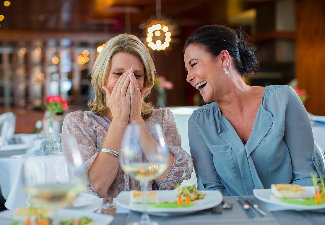 Two mature women laughing in restaurant