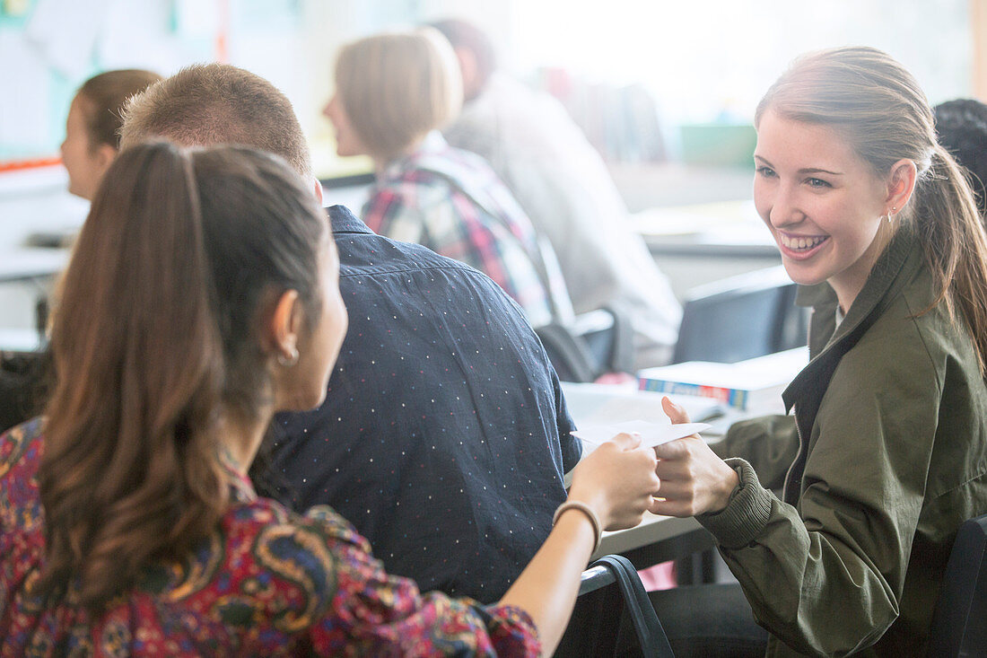 Smiling female students exchanging notes