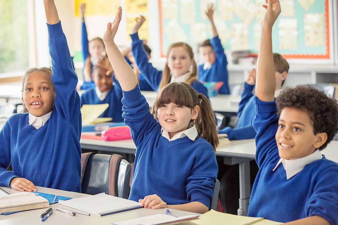 Elementary school children raising hands