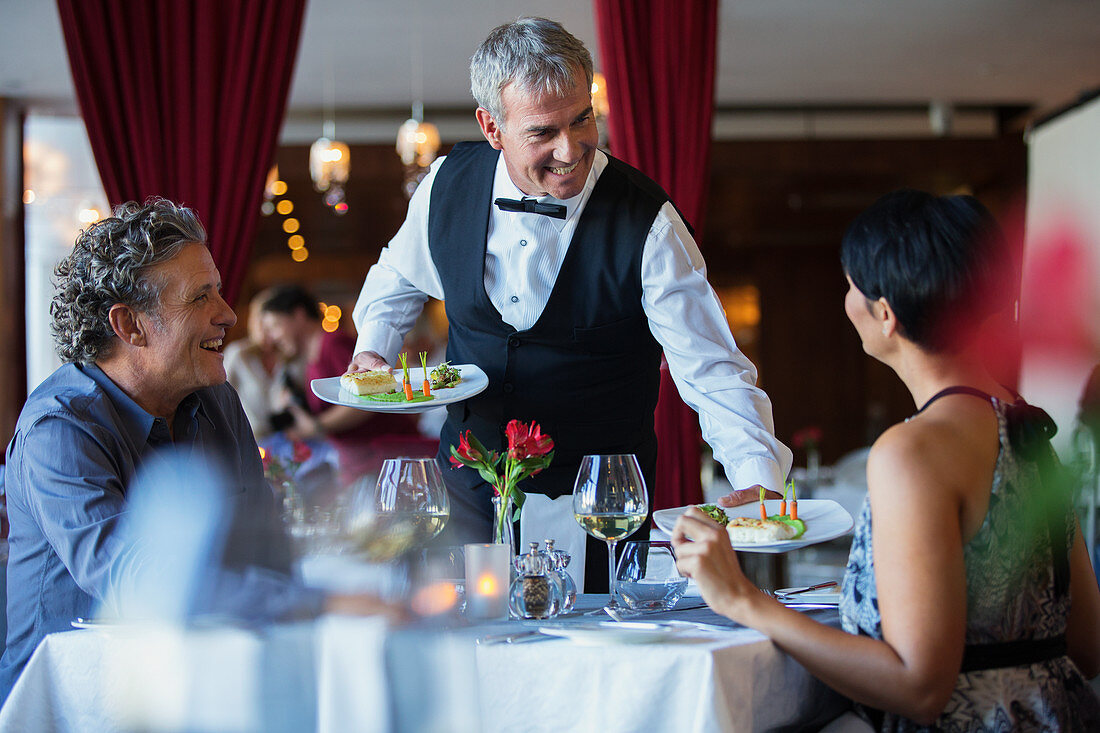 Smiling waiter serving fancy dishes
