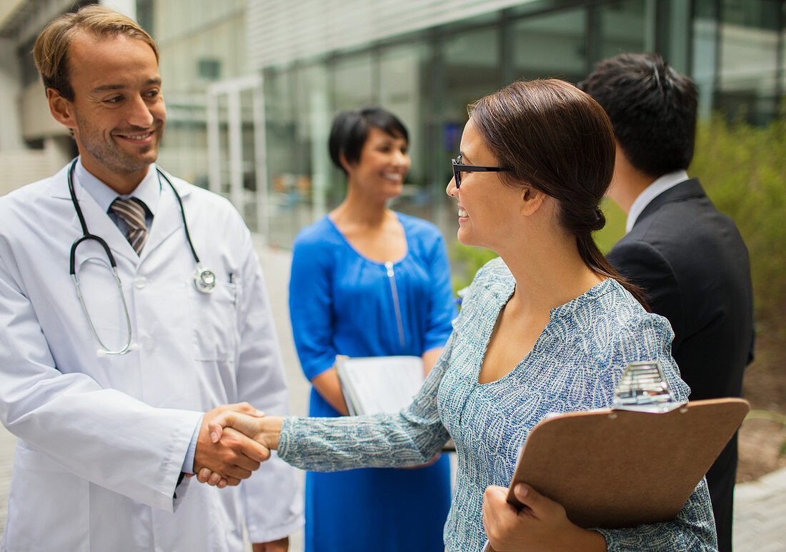Smiling doctor shaking hand with woman