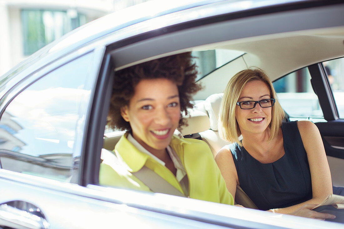 Businesswomen smiling in back seat of car
