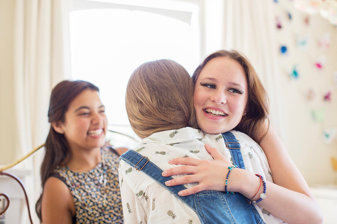 Three teenage girls embracing in bedroom