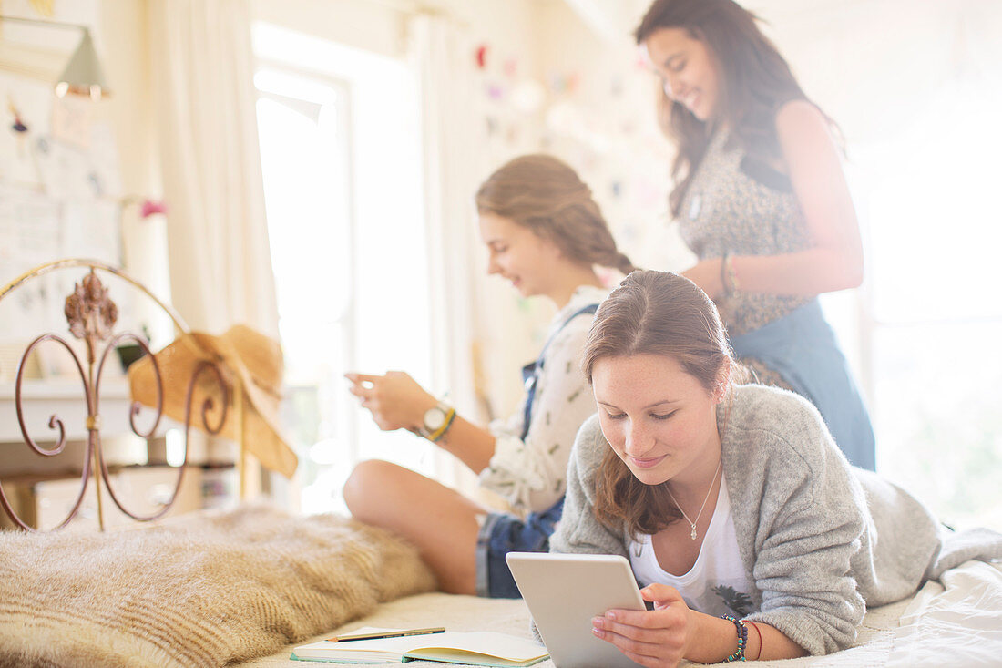 Three teenage girls relaxing in bedroom