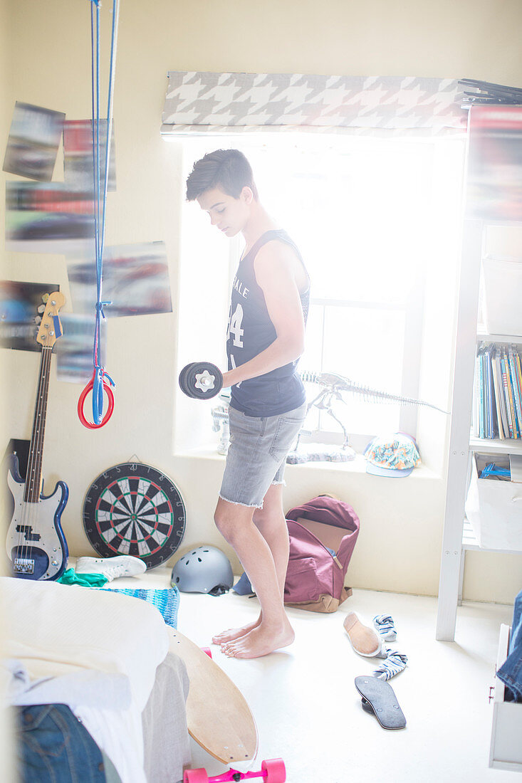 Boy exercising with dumb bell in his room