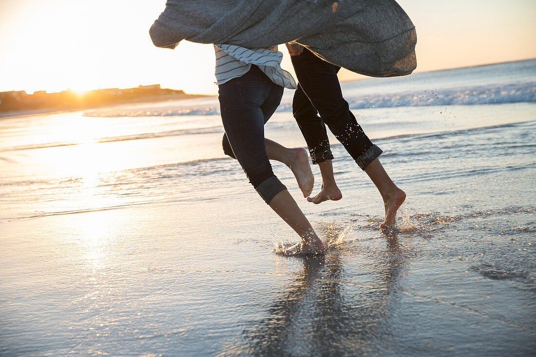 Legs of young couple running at sunset