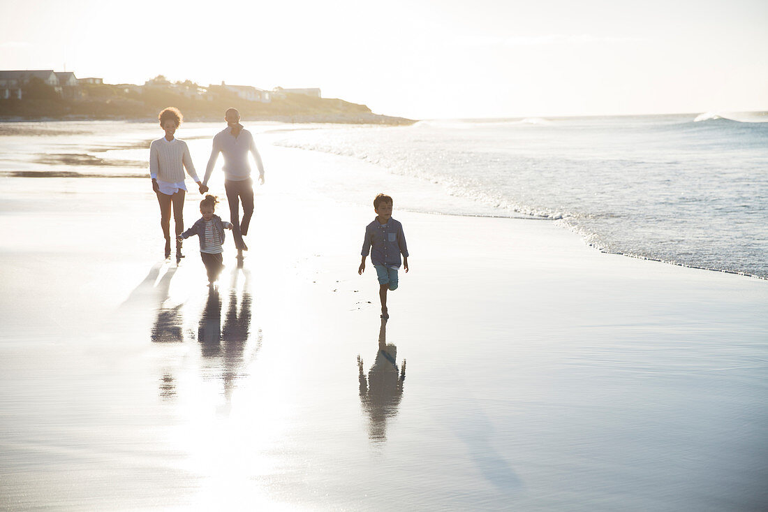 Family walking on beach at sunset