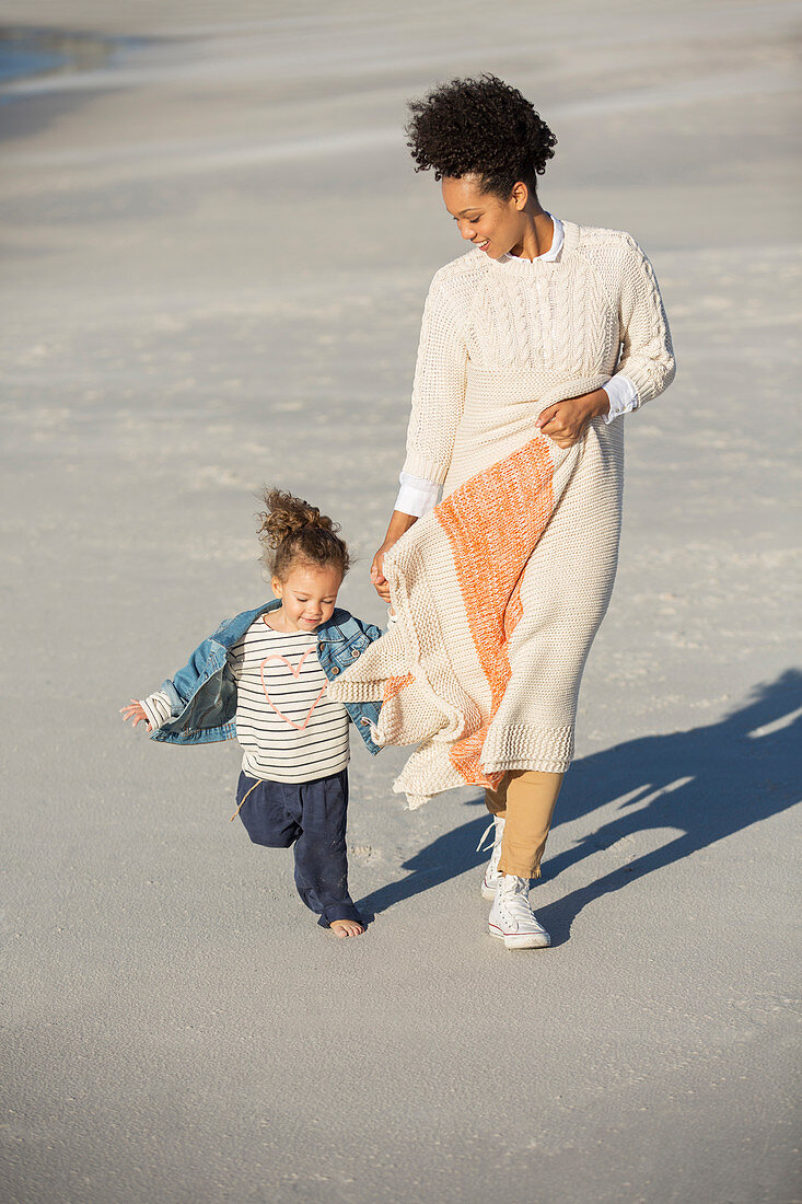 Mother and daughter walking on beach