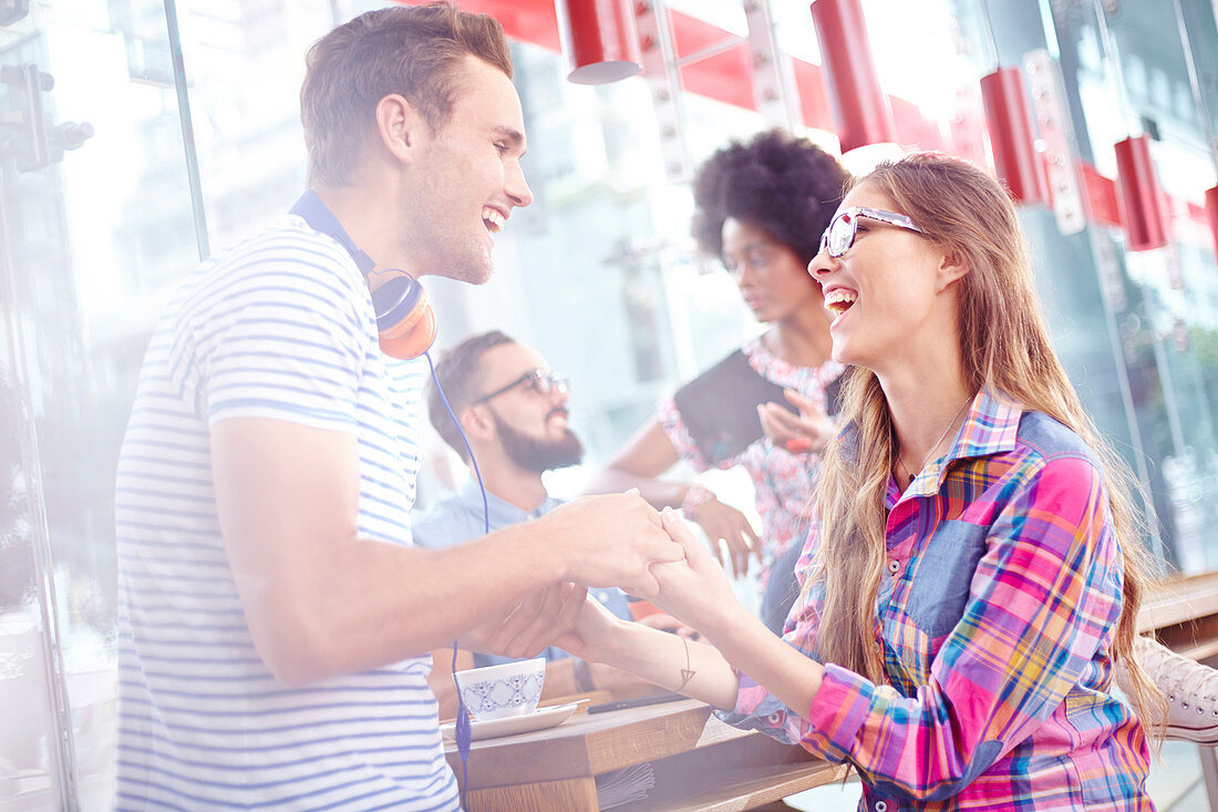 Couple laughing and holding hands in cafe