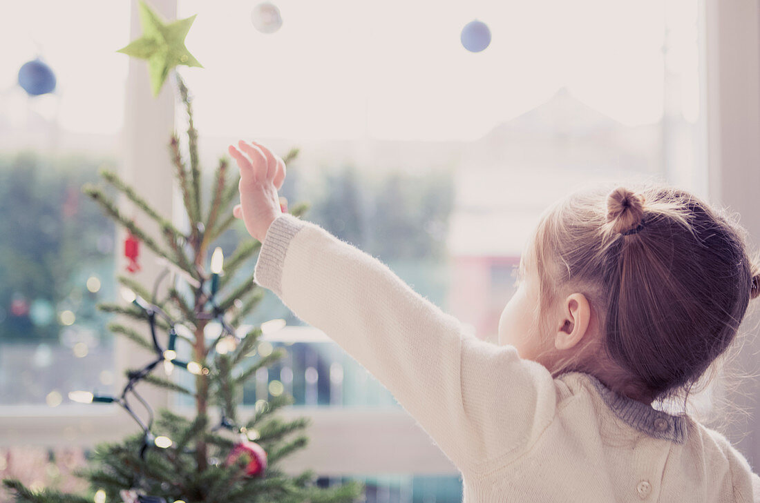 Girl reaching for start on Christmas tree