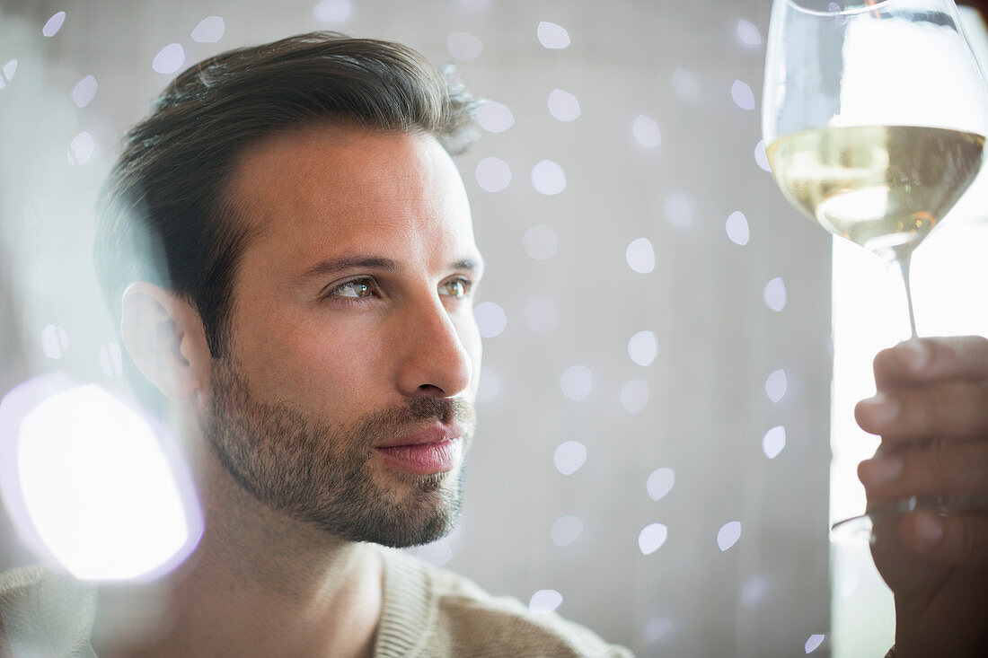 Close up serious man examining white wine
