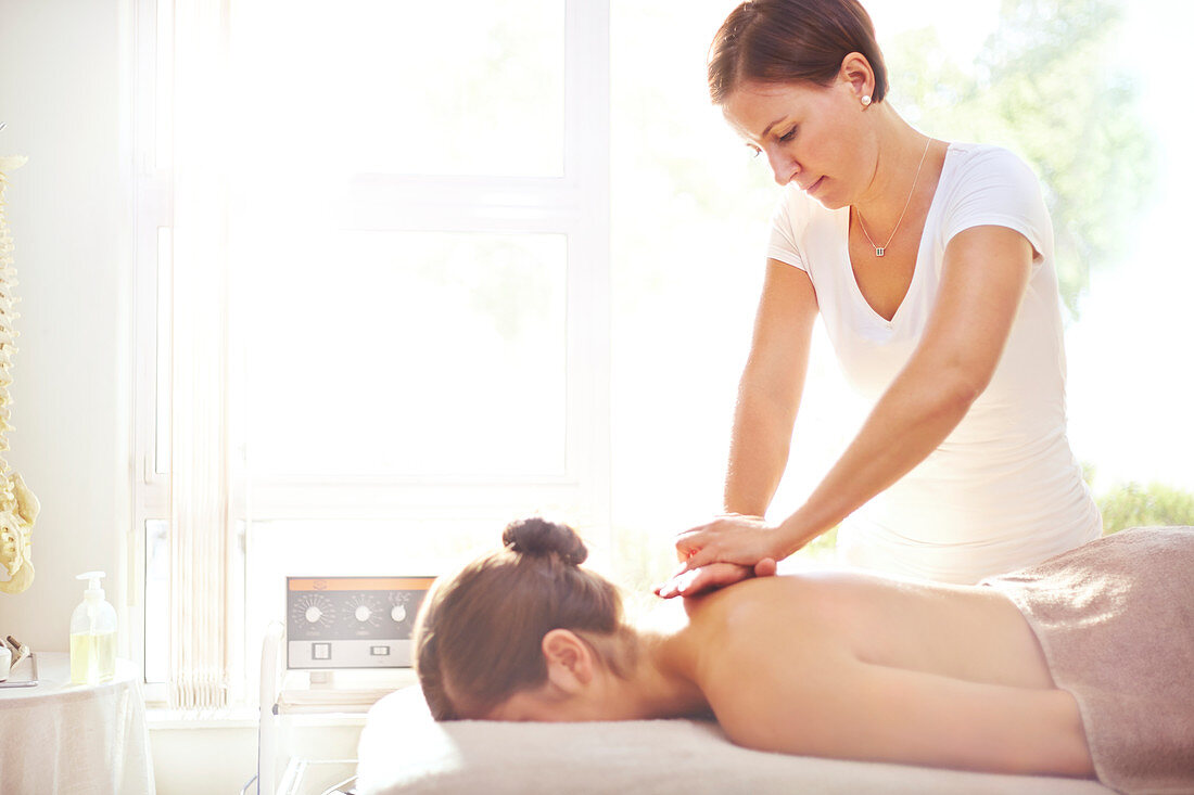 Woman receiving massage by masseuse