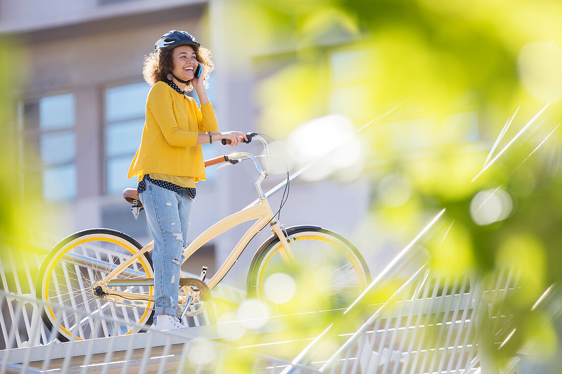 Smiling woman talking on bicycle in city