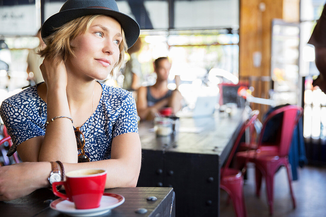 Pensive woman in hat with coffee