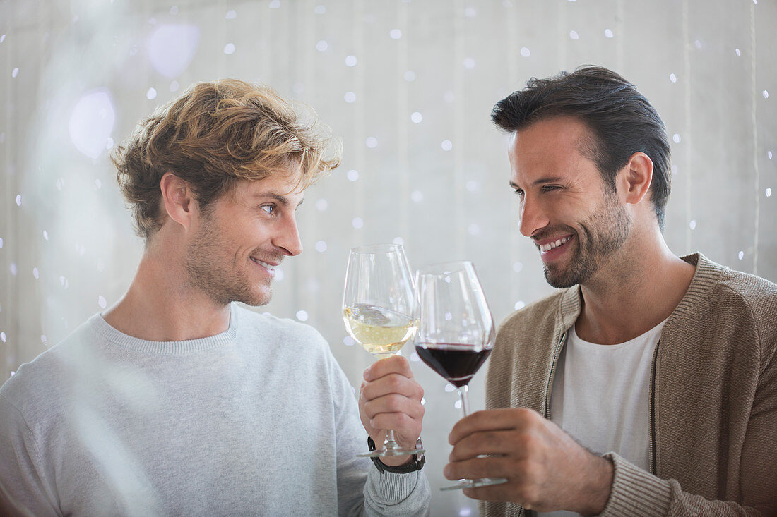 Smiling men toasting wine glasses