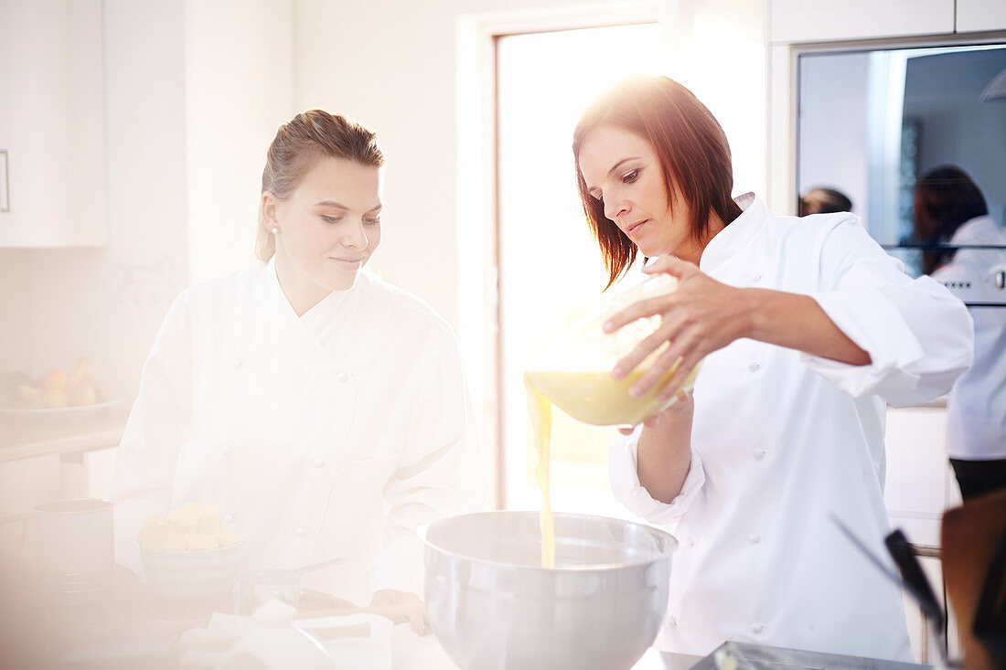 Chefs baking pouring batter in bowl