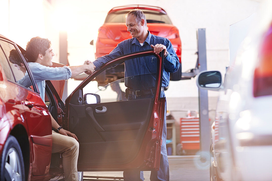 Mechanic and customer in car handshaking