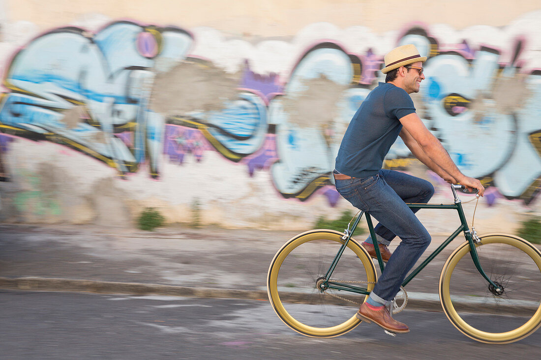 Hipster man riding bicycle on road