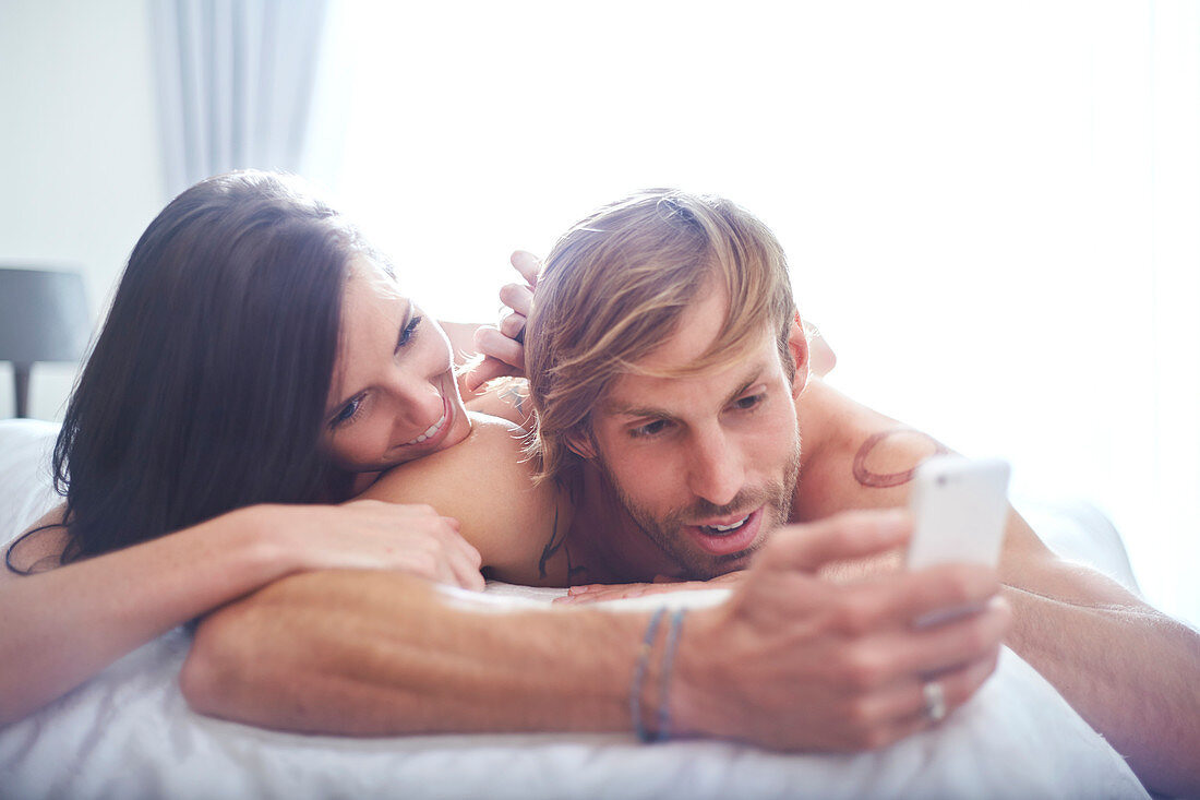 Couple relaxing on bed texting