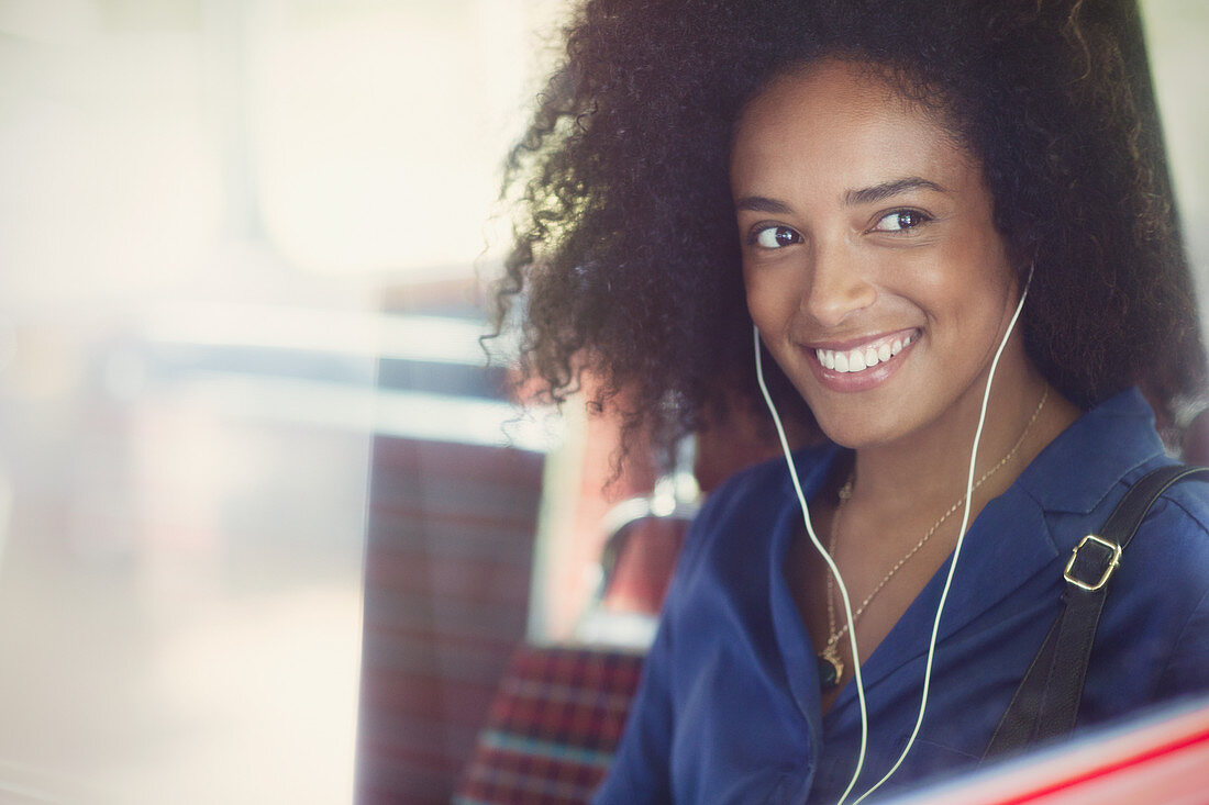 Woman with afro listening to music on bus