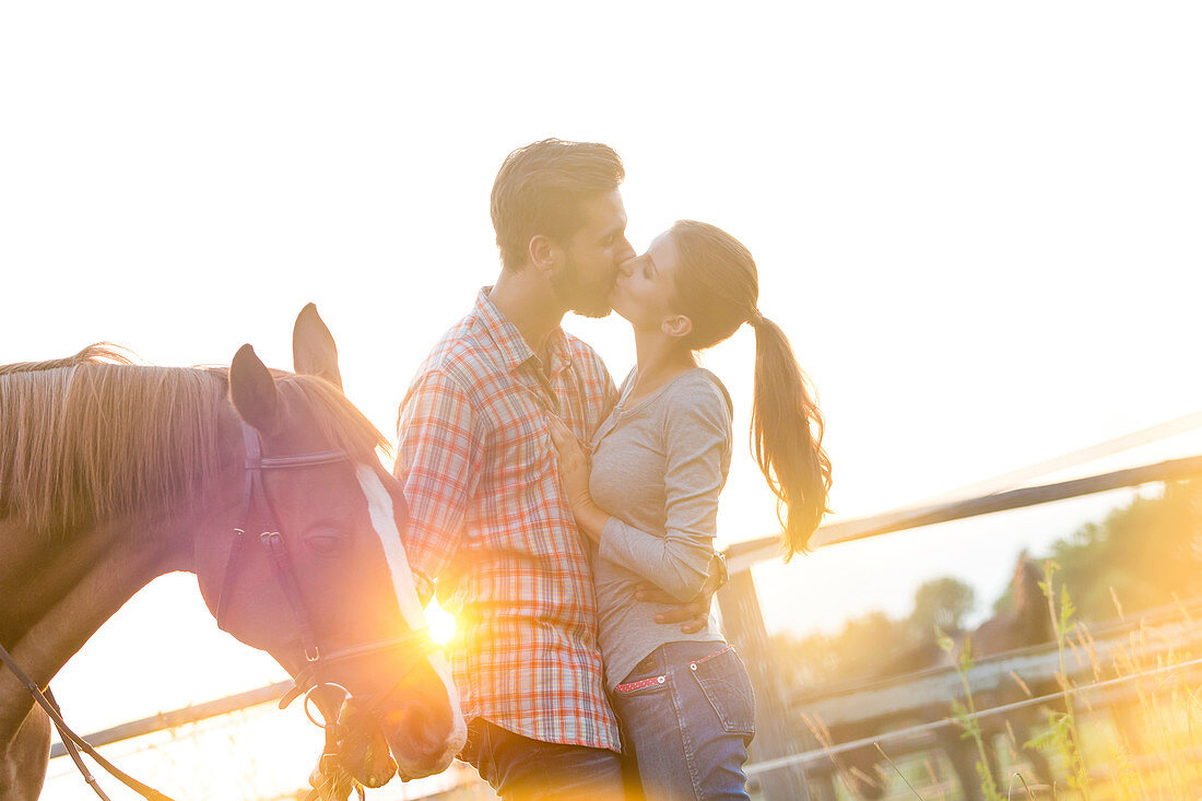 Couple kissing next to horse