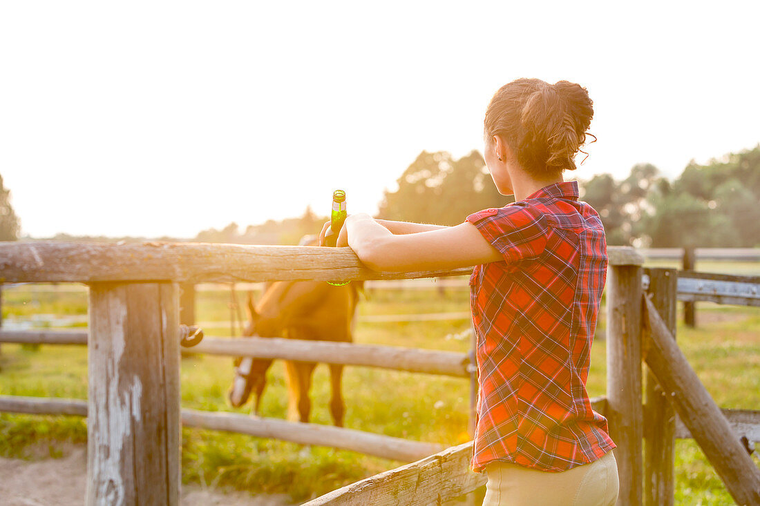 Woman drinking beer and watching horse