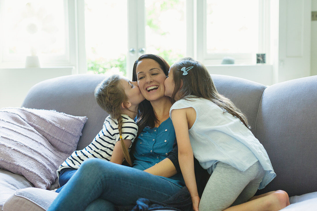 Daughters kissing mother's cheeks