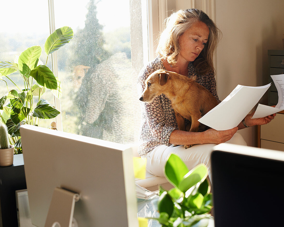 Woman with dog in sunny home office