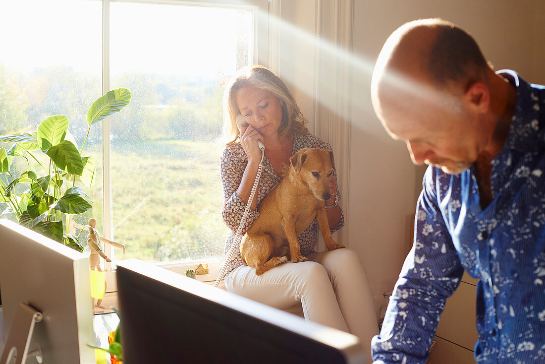 Couple with dog in sunny home office