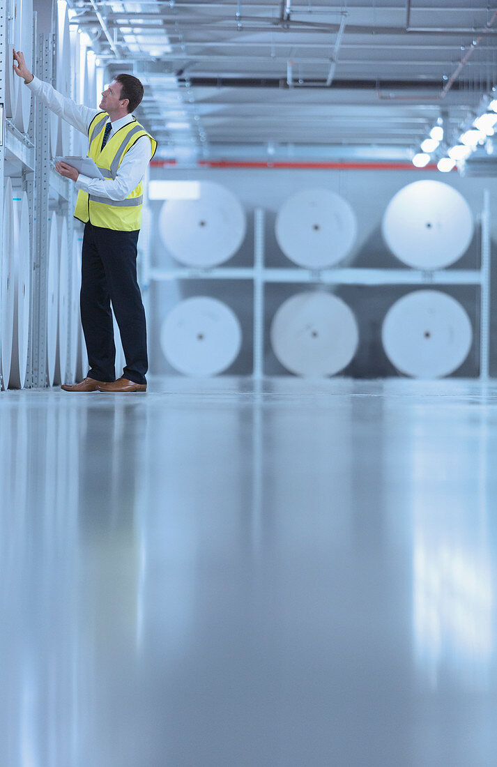 Worker examining large paper spools