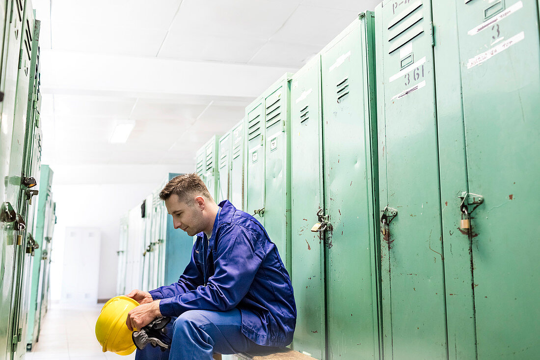 Worker holding hard-hat in locker room
