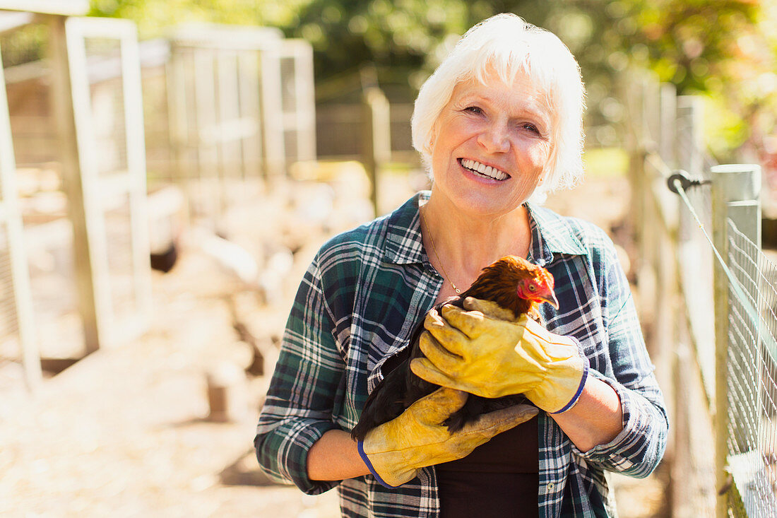 Woman holding chicken near coops
