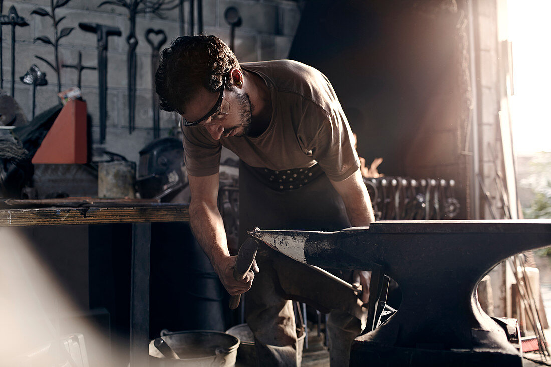 Blacksmith working at anvil in forge