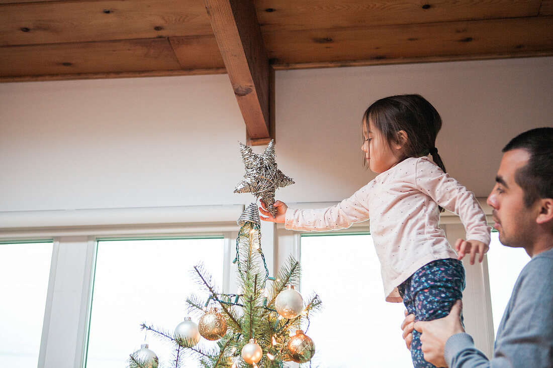 Toddler putting star on Christmas tree
