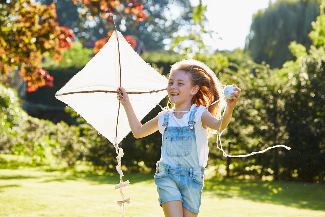 Girl running with kite in garden